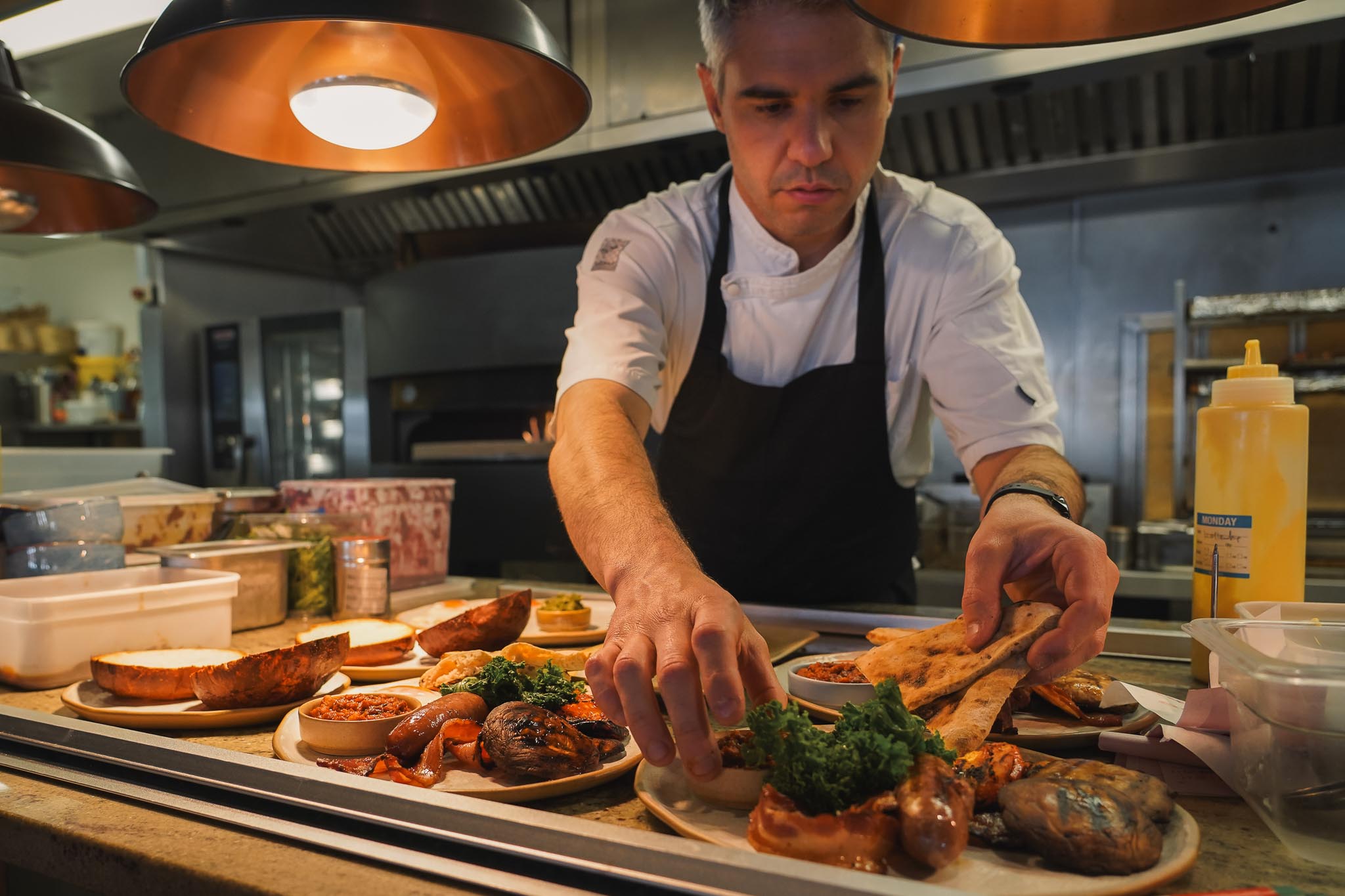 A chef plating sharing dishes at the pass in The Granary kitchen
