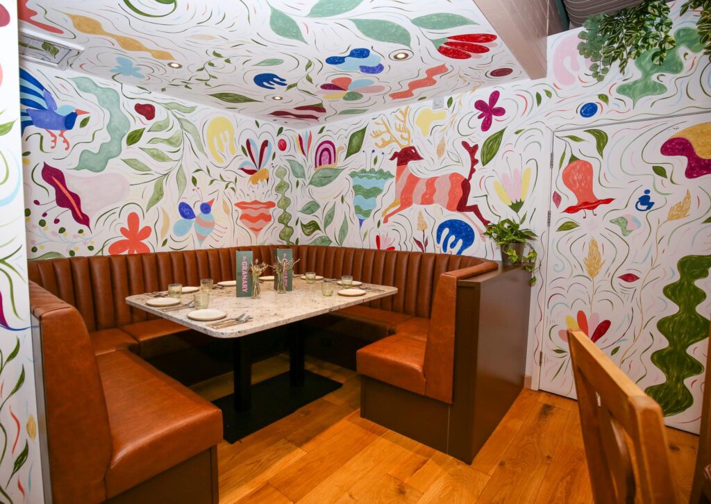 The Mural Booth, a leather booth surrounded by Ellen Donohue's hand-painted murals of birds, animals and plants at The Granary
