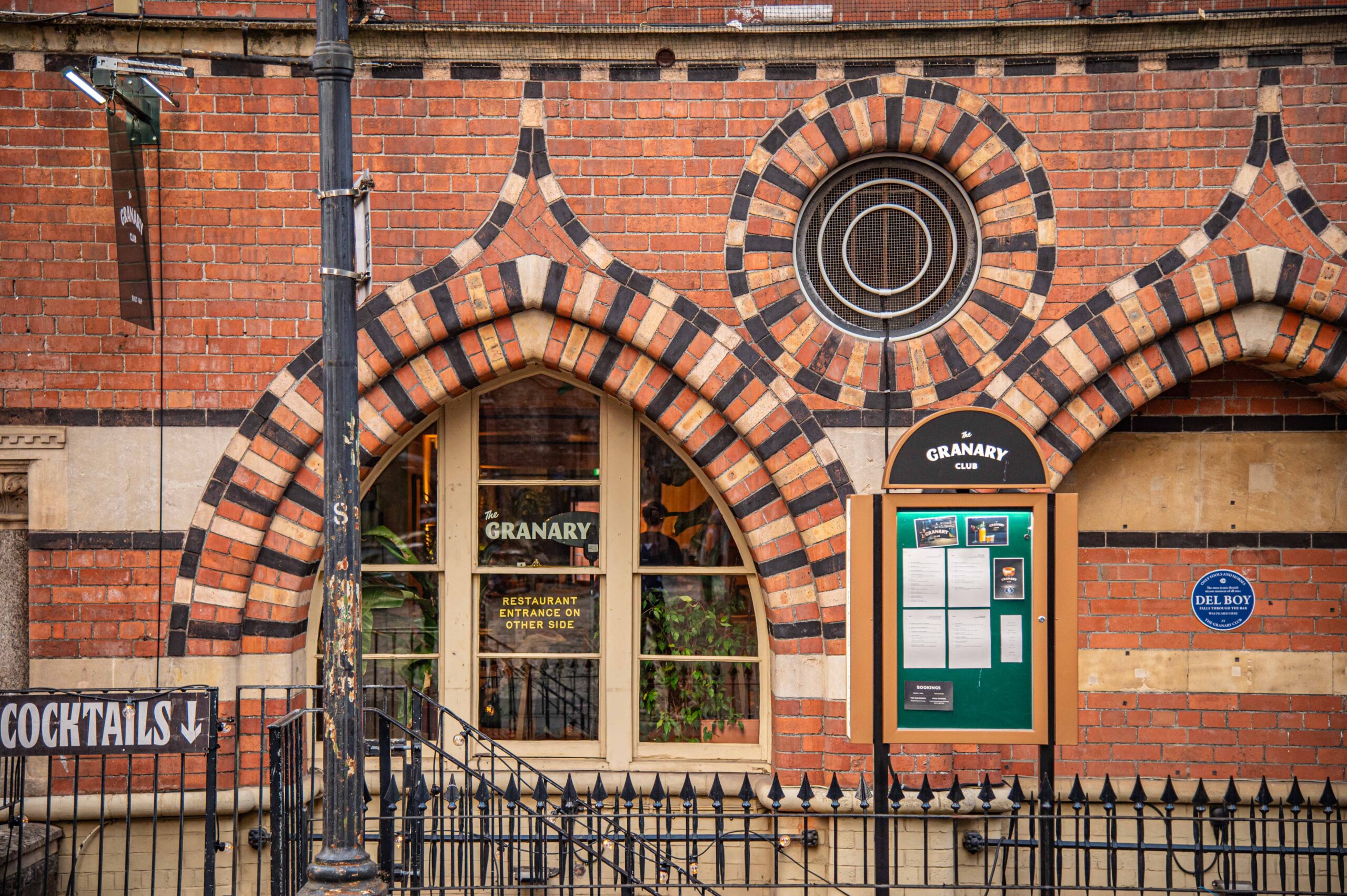 The Granary Club entrance in the patterned brickwork of The Granary, with a blue Only Fools and Horses plaque reading "Del Boy falls through the bar was filmed here at The Granary Club"