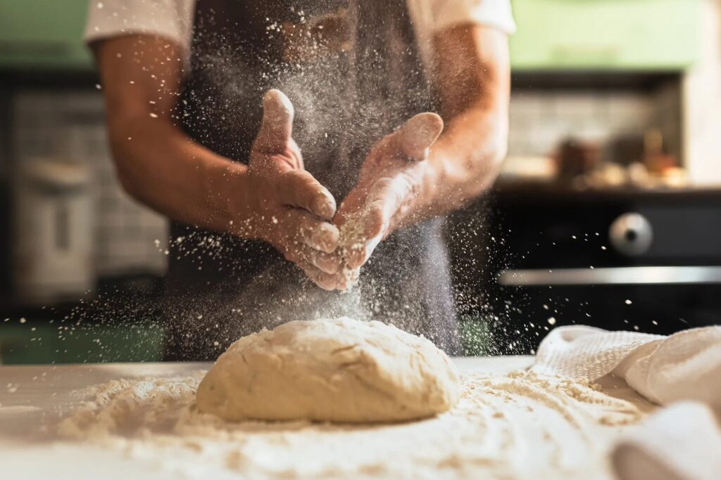 Hands dusting flour over a ball of dough