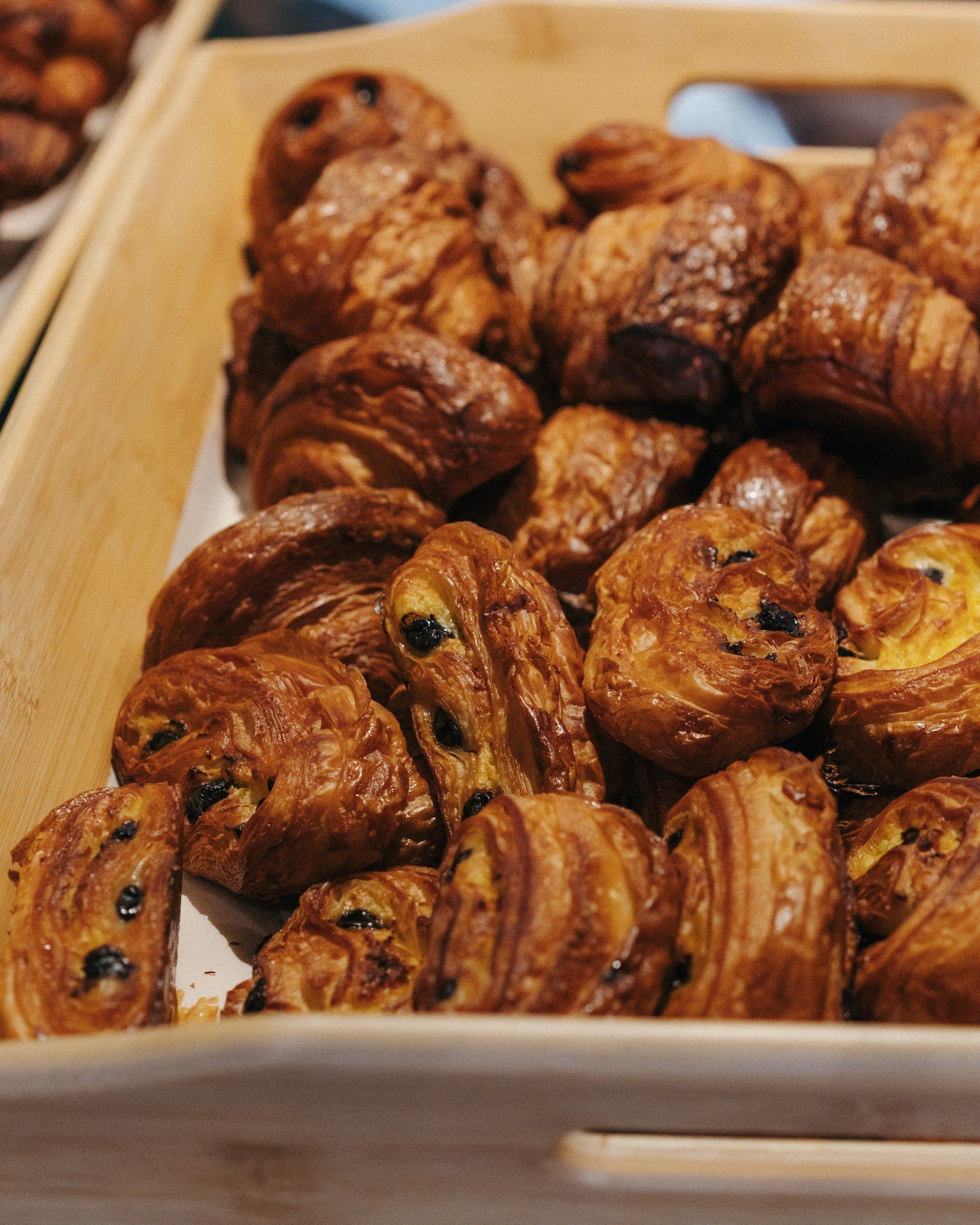 A wooden tray piled with freshly baked pastries for a group breakfast at The Granary